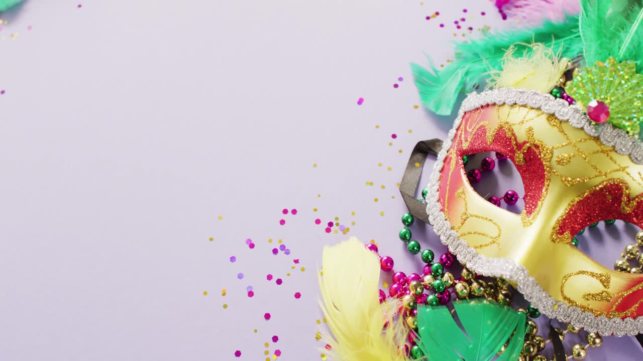 Video of carnival masquerade mask, feathers, confetti and mardi gras beads, with copy space