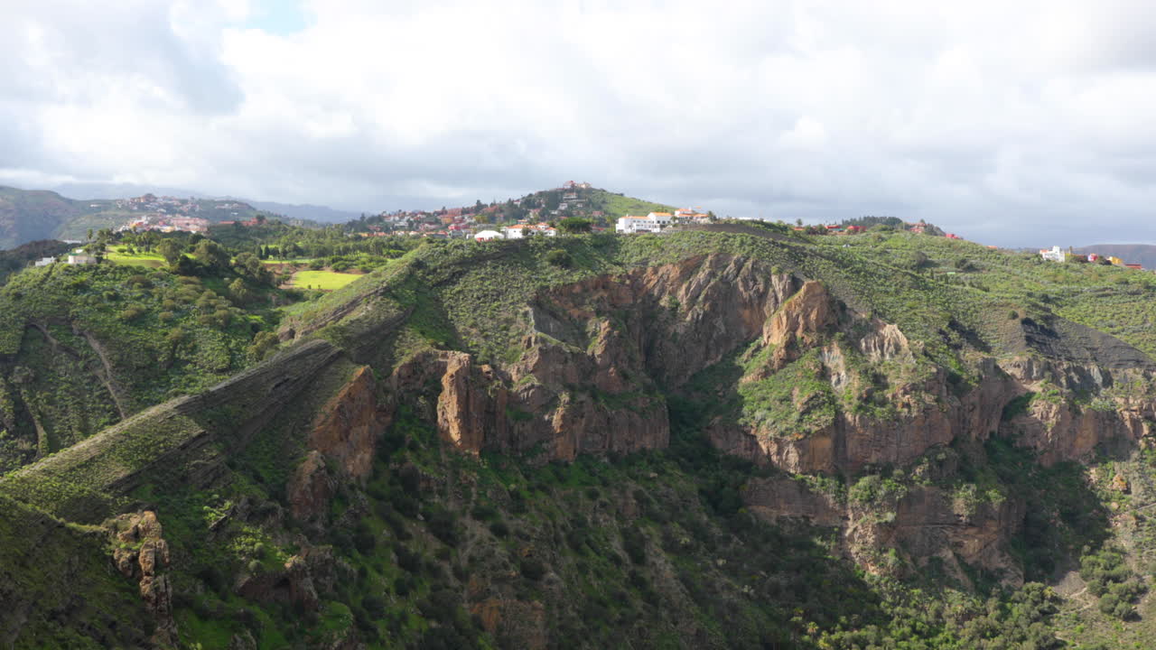 View of a hill in a small village full of houses during a sunny day with clouds moving Grand Canary Island Valley 4k slow motion capture at 60fps