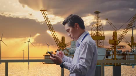 offshore engineer checking mobile phone during sunset