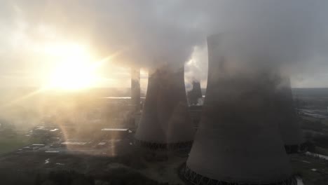 aerial slow dolly left view of uk power station cooling towers smoke steam emissions at sunrise