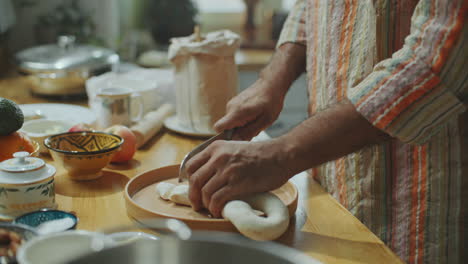 hands of chef cutting dough into small pieces on kitchen table