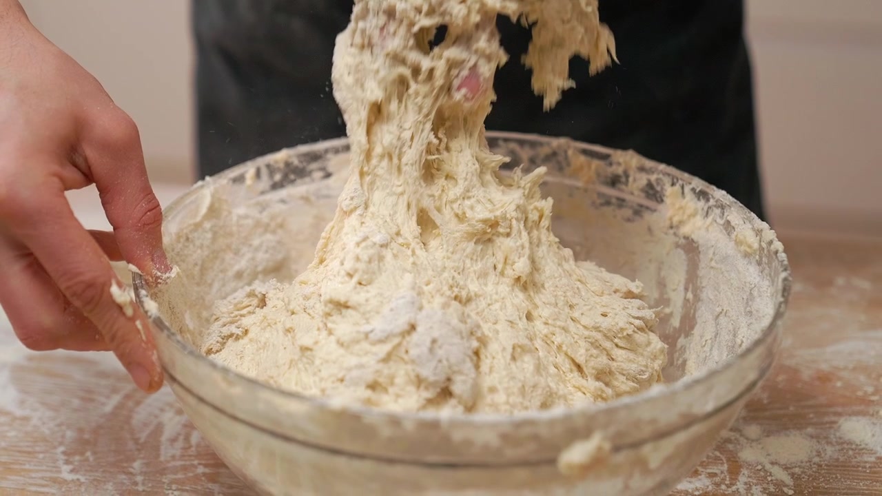 Close-up of Hands Kneading Dough in a Glass Bowl
