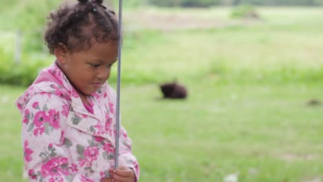 Funny-little-African-girl-making-hilarious-faces-grabbing-swing-rope-in-garden