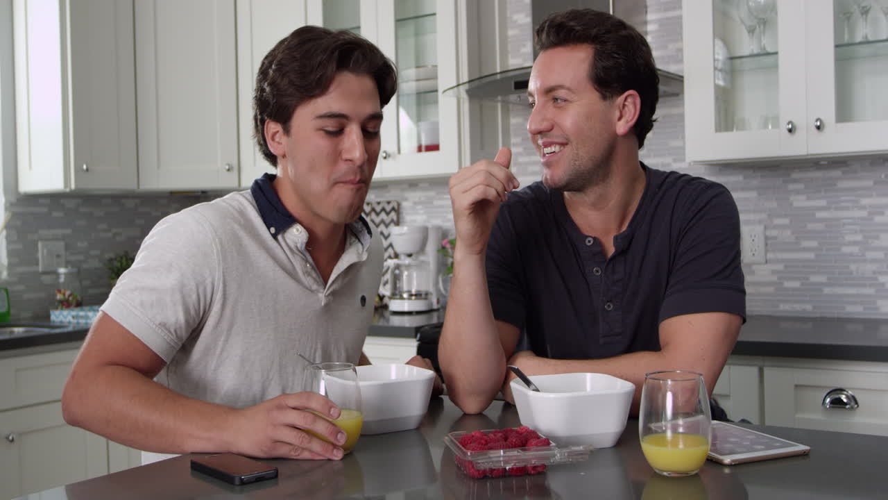 남자는 파트너에게 베리를 먹이고 아침 식사에서 태블릿을 확인합니다.
