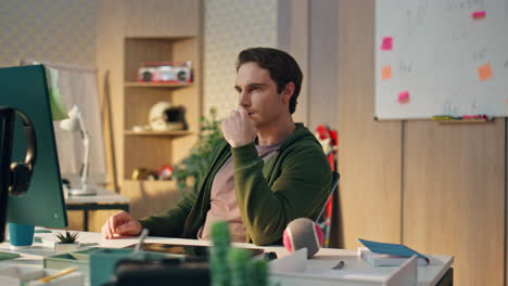 focused artist staring computer display in evening office. serious man working