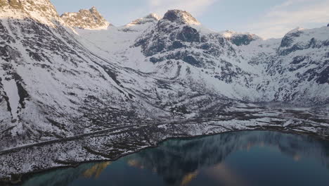 majestuosa vista de drones de la carretera a lo largo del fiordo, montañas árticas cubiertas de nieve