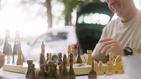 close up of a happy father and son playing chess and giving high five outdoors