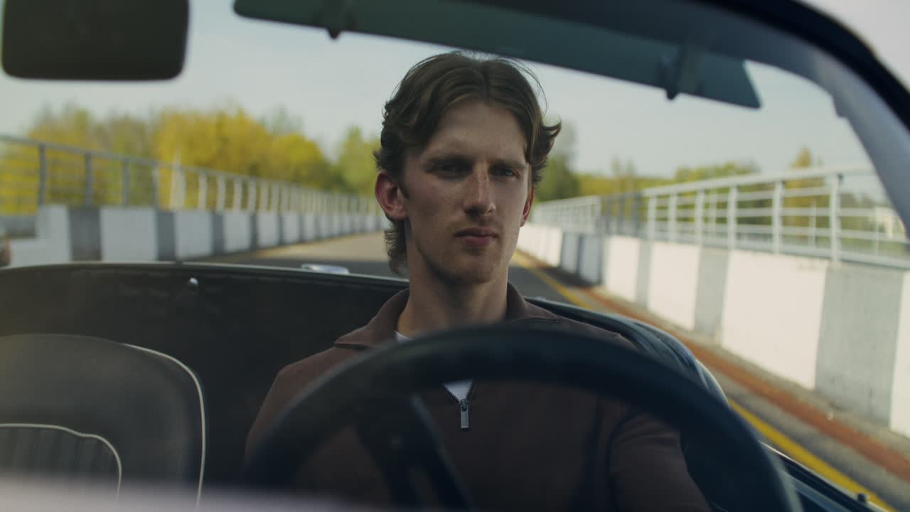 Young Man Driving a Vintage Sports Car on a Race Track