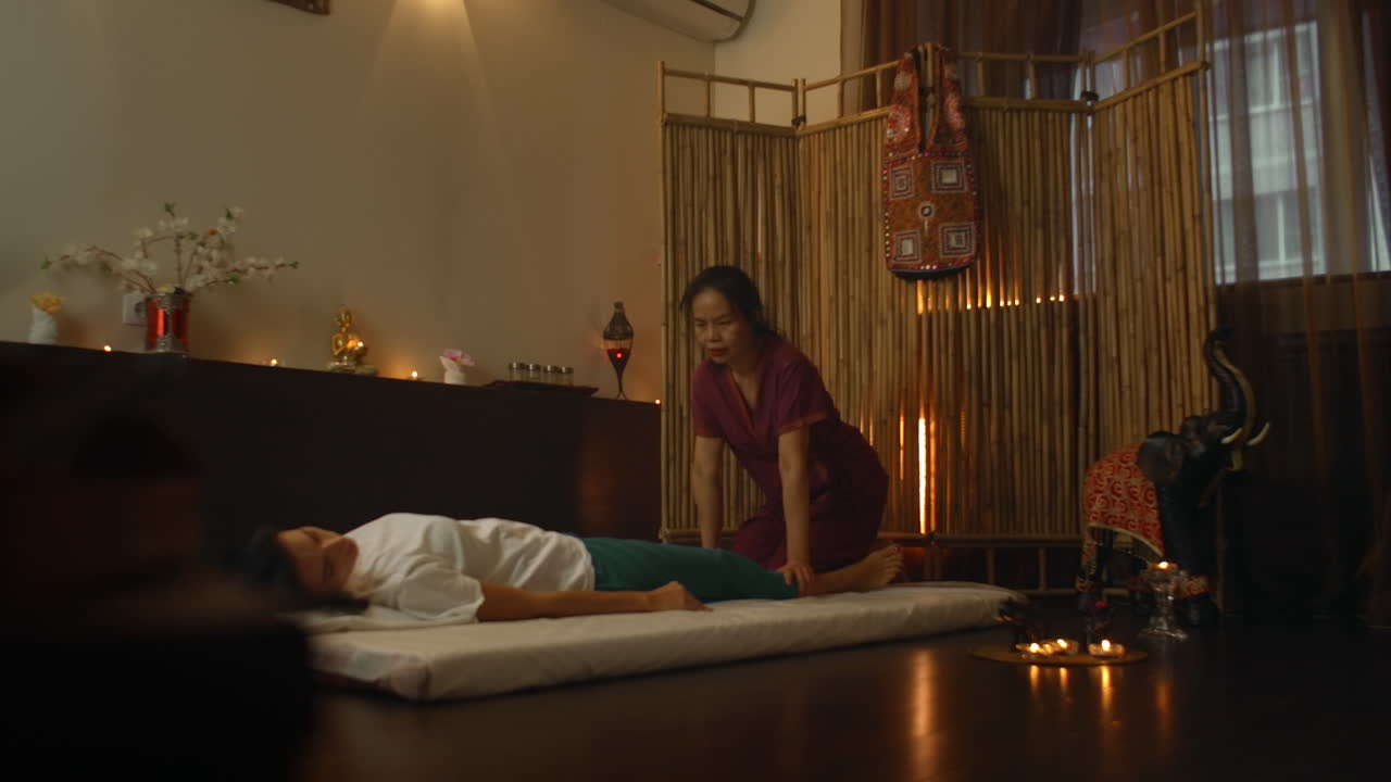 Young woman enjoying the acupressure techniques of Thai massage. Young woman lying down while enjoying the acupressure techniques of traditional Thai massage