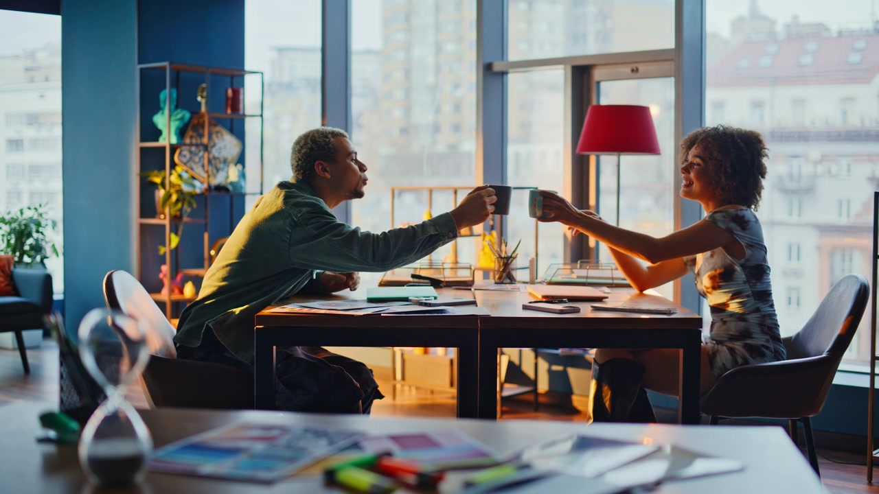 Friends laughing over coffee cinematic office. People relaxing at sunset window