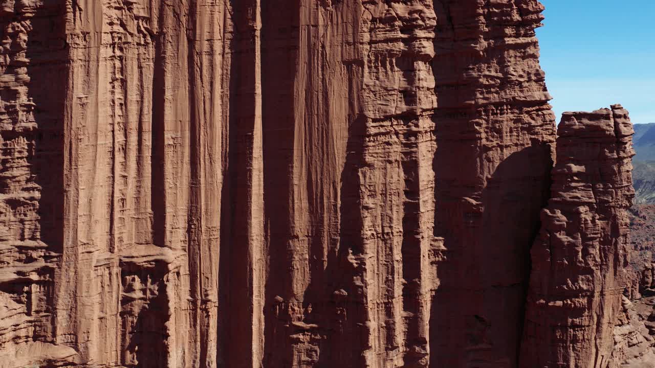 Vista aerea delle spettacolari guglie di arenaria Cutler delle Fisher Towers sormontate da arenaria Moenkopi vicino a Moab, Utah. Ripresa con avanzamento.