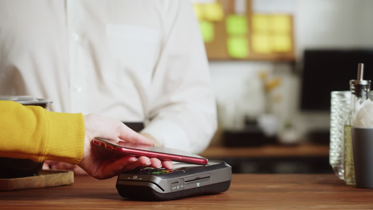 Paying with smartphone close-up, using NFC technology in a restaurant. Customer pays by mobile phone, contactless technology, touch-free payment in a cafe.