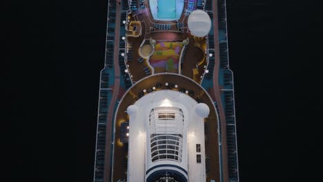 aerial tilt up shot on cruise ship deck with pool and jacuzzi along with chimney polluting while departing lahaina town, hawaii, usa at dusk