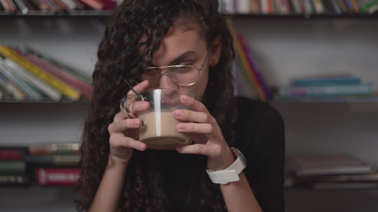 Young Woman Drinking Coffee in a Library