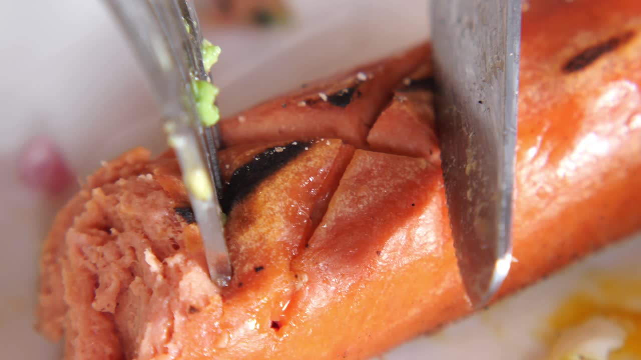 Sausage being cut with fork and knife