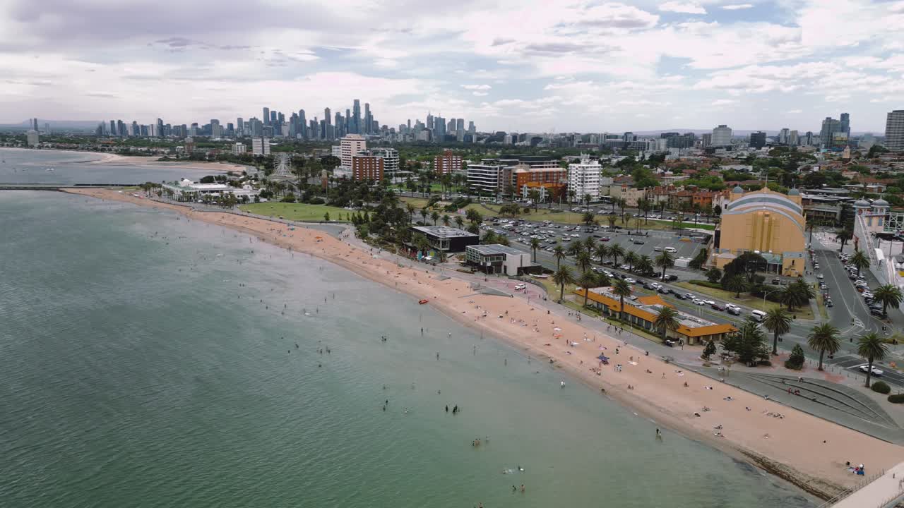 Panning reveal of St Kilda Beach in Melbourne Australia on a Sunny Summer, with a huge crowd showing at the beach.