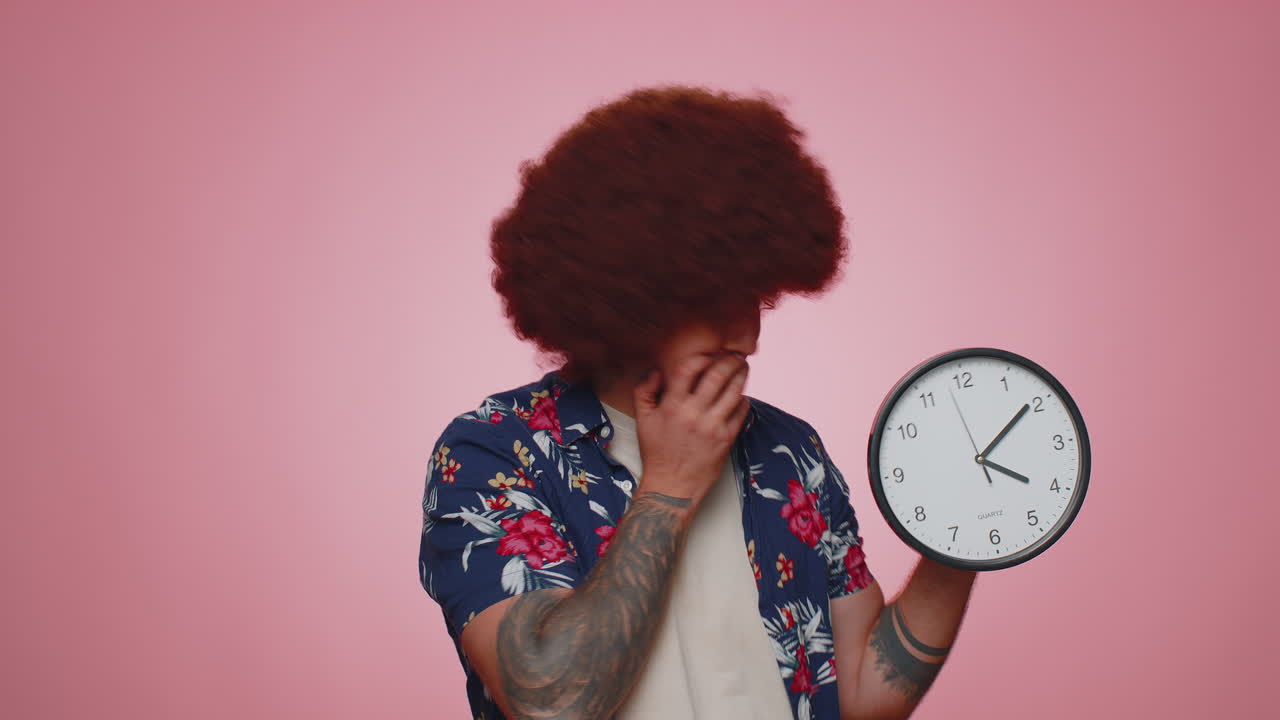 Confused man with anxiety checking time on clock, running late to work, being in delay, deadline