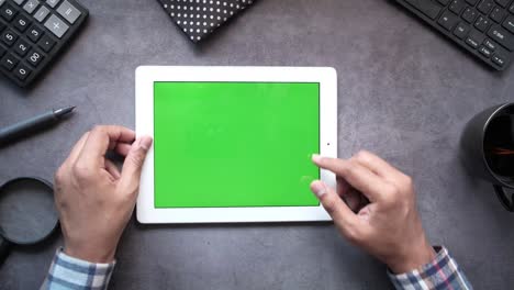 persona usando una tableta con una pantalla verde en un escritorio