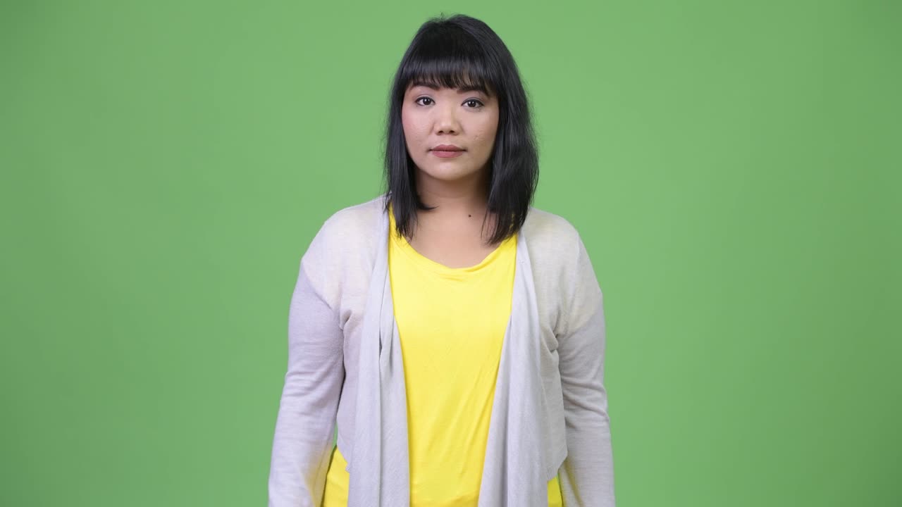 아름다운 행복한 아시아 여성이 위를 가리키면서 생각하고 있습니다.