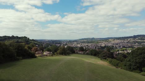 Aerial, ascent from a young boy drawing, sat in green fields, revealing City of Bath on a summer's day,