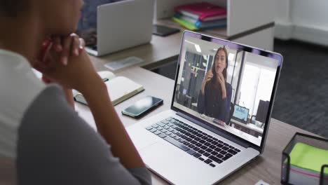 Mid-section-of-african-american-woman-having-a-video-call-on-laptop-with-female-colleague-at-office