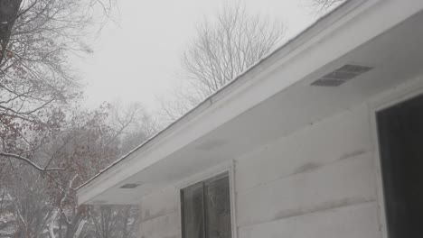 snow falling heavy on a small roof