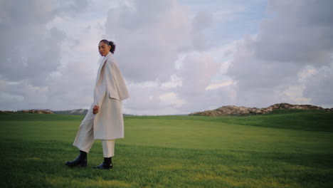 mujer tranquila caminando campo en las vacaciones de primavera. hermosa modelo sereno mirada cámara