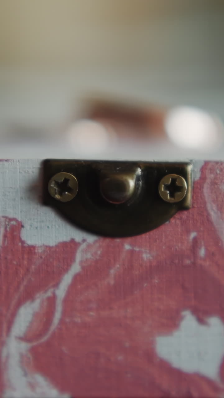 Craft wooden box with pink paint smears for wedding rings on stand extreme closeup. Bridal ceremony design ideas. Handmade decorative element