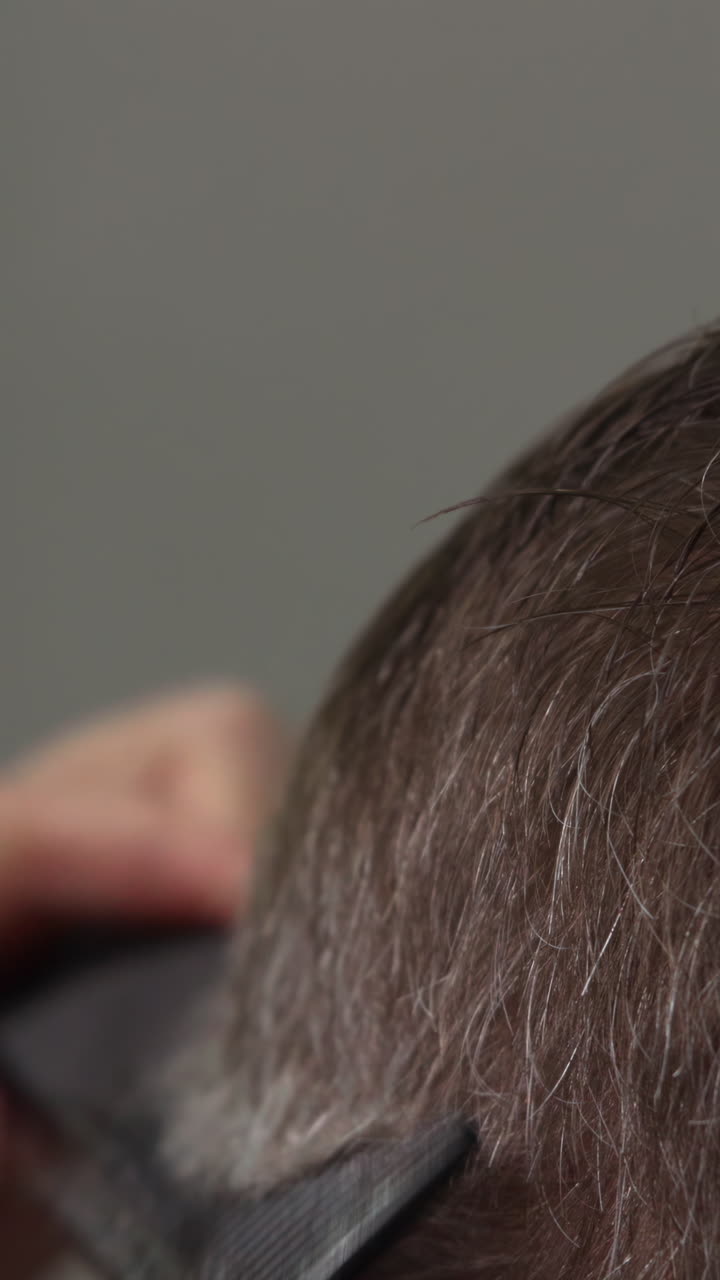 Professional Hairdresser Cutting Client's Hair with Scissors and Comb