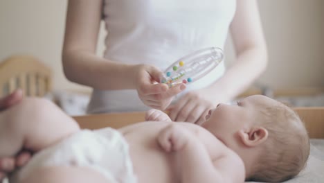 un bebé lindo se acuesta en la mesa de cambio y la enfermera masajea las piernas