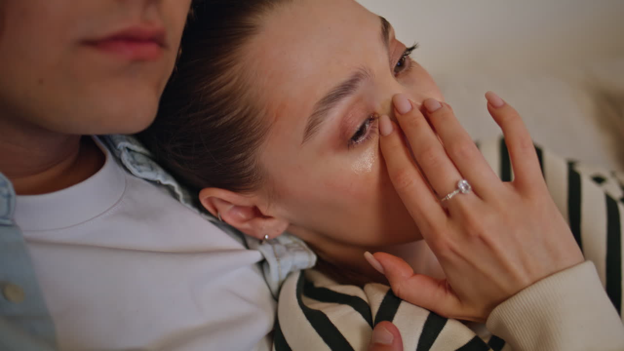 Young pair watching melodrama TV sitting comfortable apartment sofa closeup