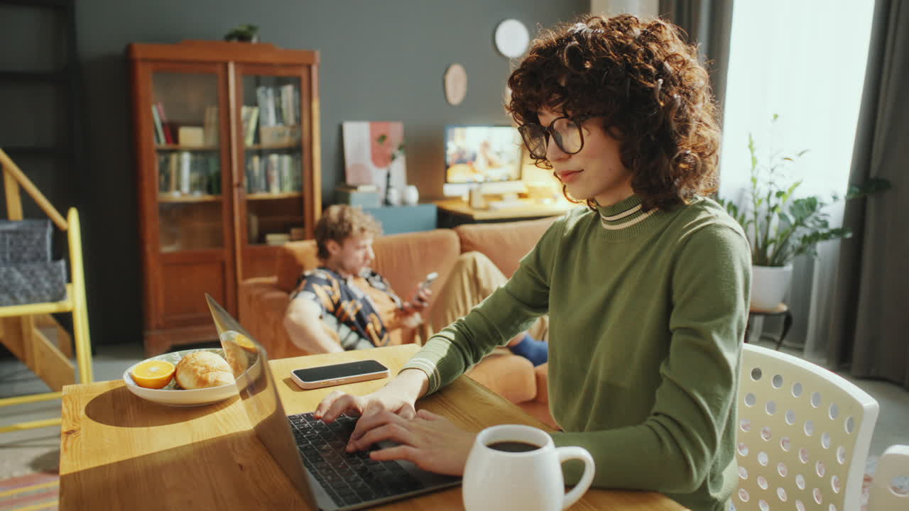 Young Woman Working Online on Laptop in Cozy Apartment