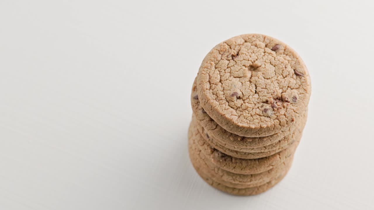vertical stack of round chip cake cookies with chocolate on white surface slow rotating looped background