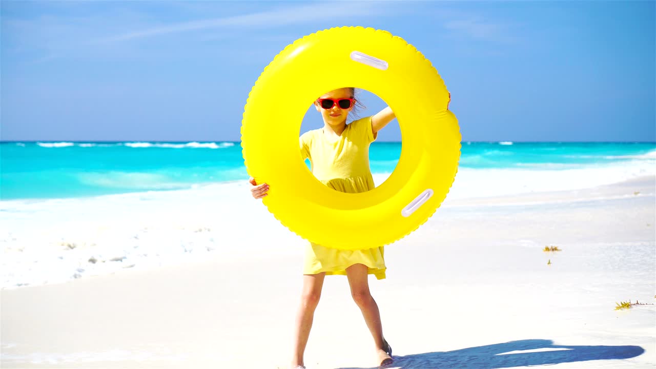 Little girl with inflatable rubber circle on beach vacation