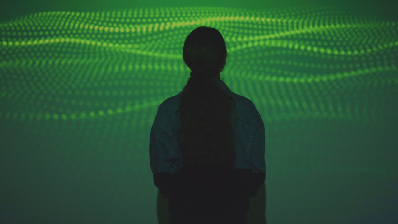 mujer visitando una exposición de arte inmersiva con proyección de formas y patrones en la pared 9