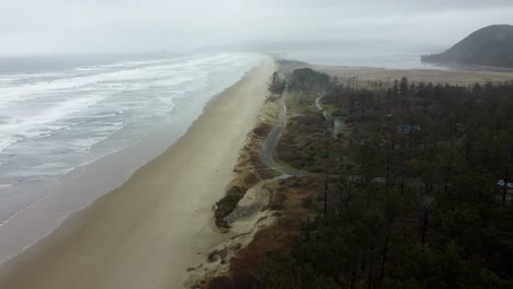 US, Oregon, Tillamook, Cape Lookout, 2025-02-19 - Drone view of the oregon coast in winter. Flying along the waves and sand and trees in the rain.