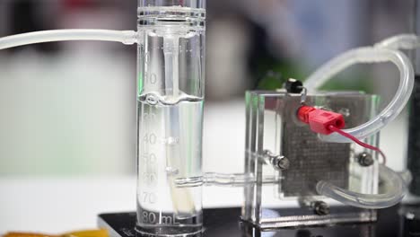 hydrogen bubbles forming in a plastic cylinder filled with water, a fuel cell demonstrator splits water into oxygen and hydrogen, slow motion