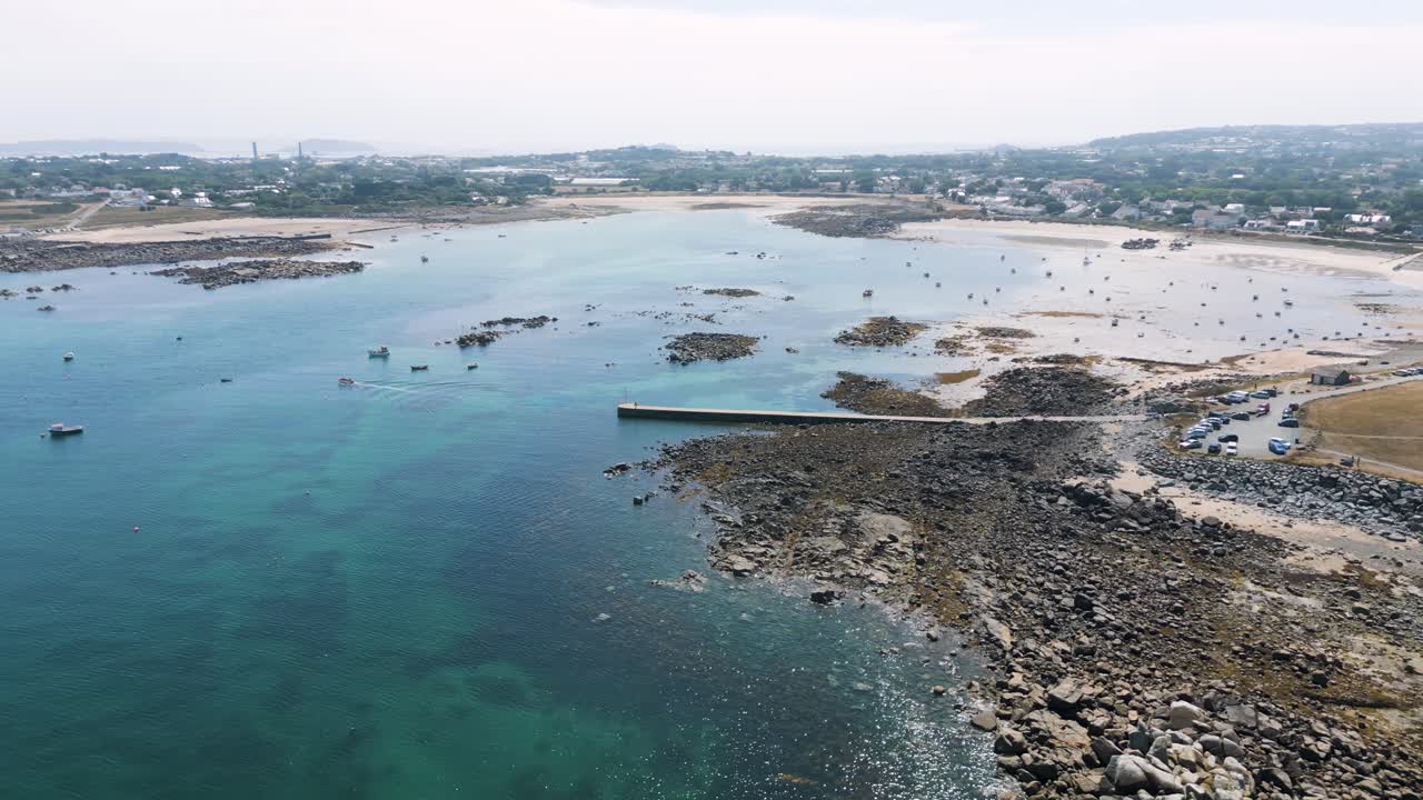 Volo circolare di drone ad alta quota su baie e un promontorio che sorvola un mare cristallino, barche all'ancora, una strada rialzata, una torre di Martello e splendide spiagge dorate.