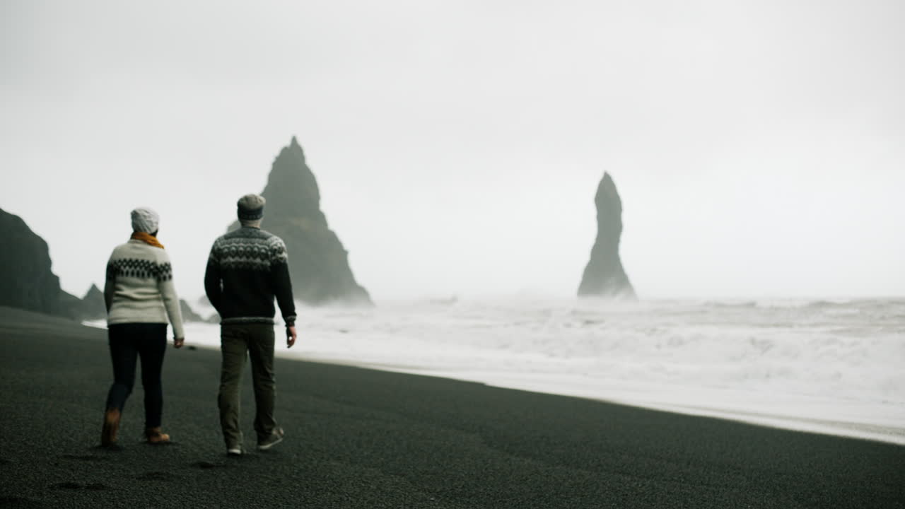 Couple walking on a black sand beach in Iceland