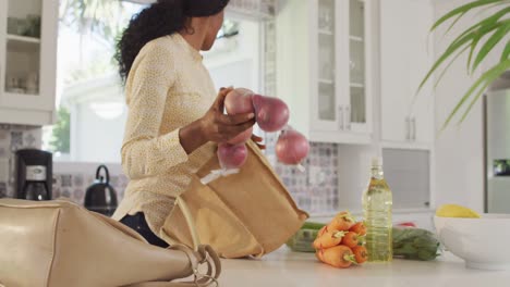 video de la sección media de una mujer afroamericana desempaquetando comestibles en la cocina