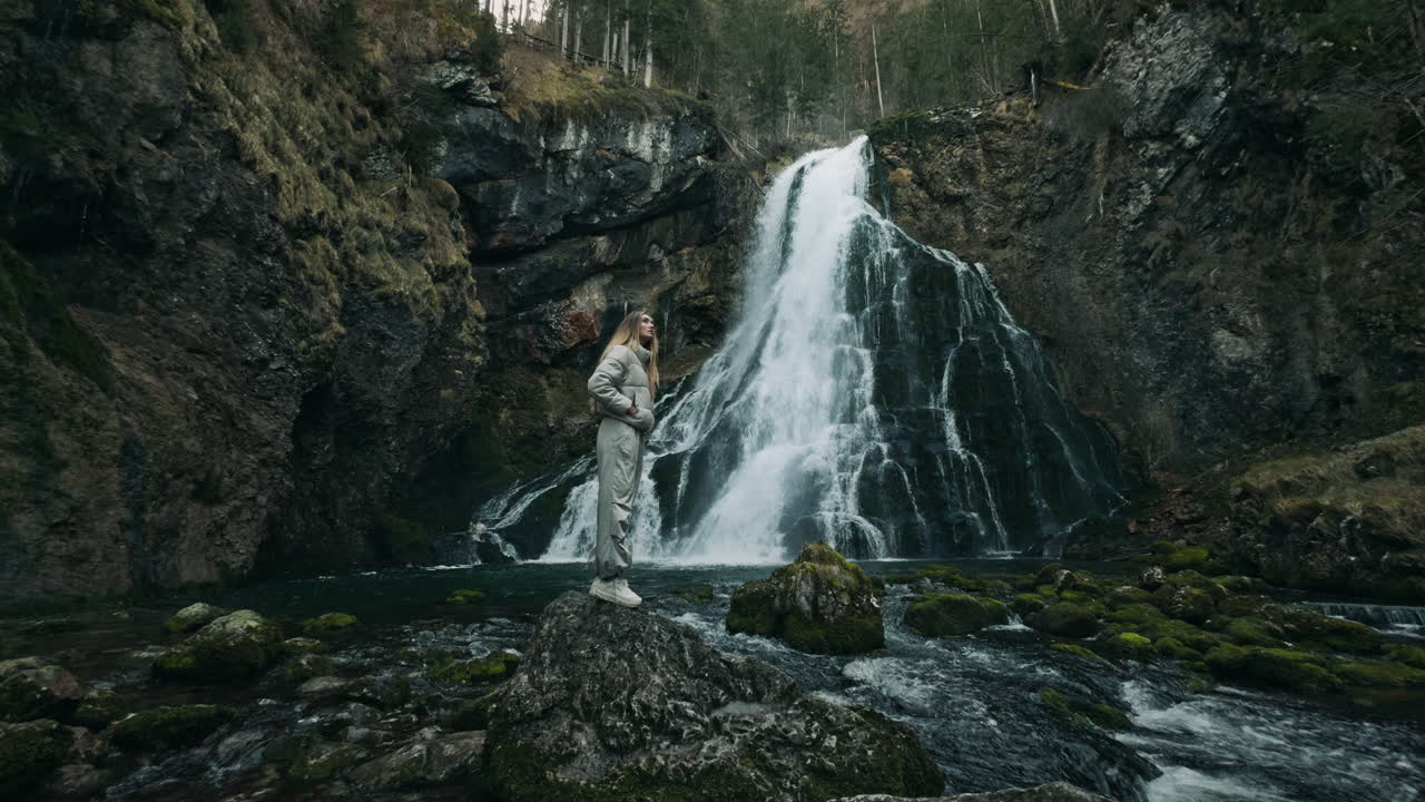 Kvinne står ved en foss i en skog