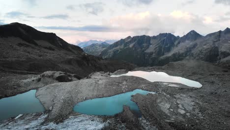 Aerial-flyover-over-the-glacial-lakes-of-the-Witenwasseren-glacier-towards-the-peaks-of-Uri,-Switzerland