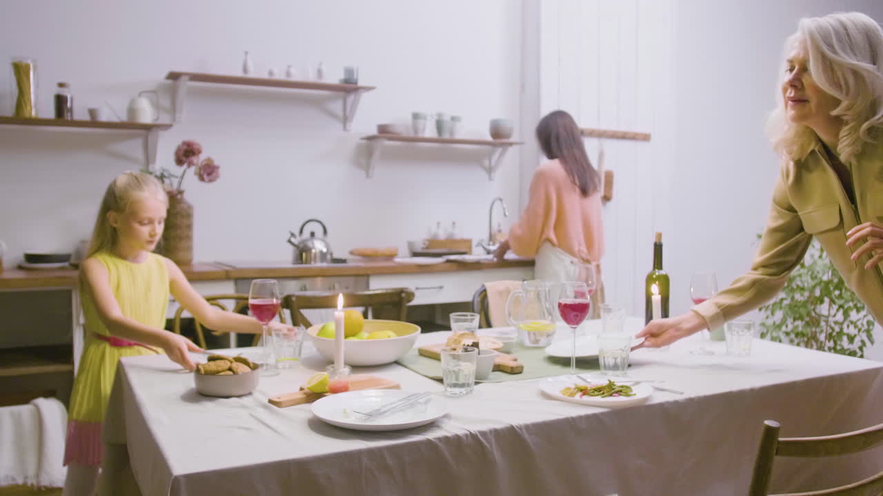 어머니, 딸, 할머니가 가족 저녁 식사 후 테이블에서 접시를 치우고 있습니다.