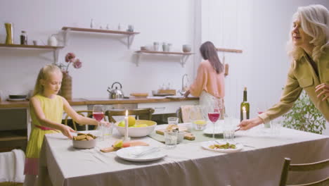 Mother,-Daughter-And-Grandmother-Removing-The-Plates-From-The-Table-After-Family-Dinner
