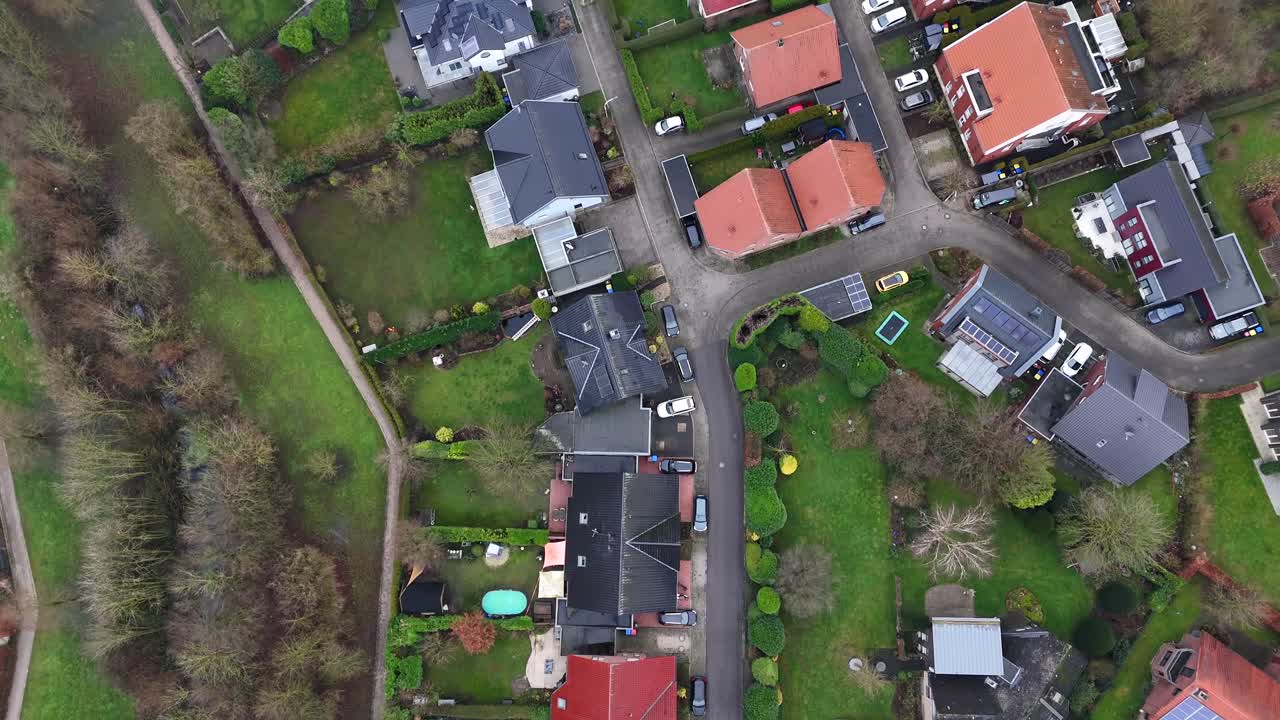 Luxury homes with solar panels in suburb district of american town. Car on street near agricultural farm fields in winter. Aerial top down flyover.