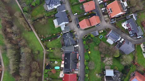 luxury homes with solar panels in suburb district of american town. car on street near agricultural farm fields in winter. aerial top down flyover.