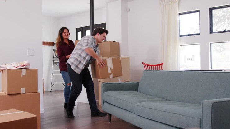 Couple Carrying Removal Boxes Into New Home On Moving Day