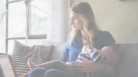 Animation-of-social-distancing-message-flashing-over-Caucasian-woman-feeding-her-baby