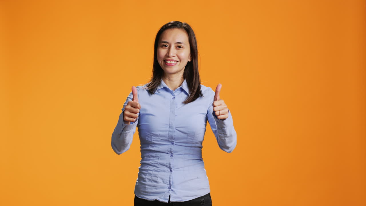 modelo asiático presentando el pulgar hacia arriba símbolo en el estudio