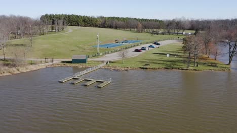 Dolly-pedestal-flying-through-jacobson-park-lexington-kentucky-over-a-lake-and-basketball-court-on-a-sunny-day-4k